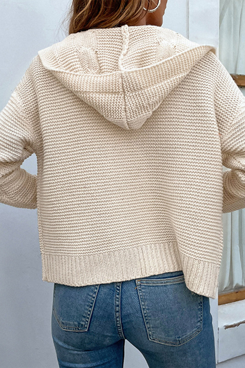 Cable-knit hooded cardigan with dropped shoulders, open front, and cream color.