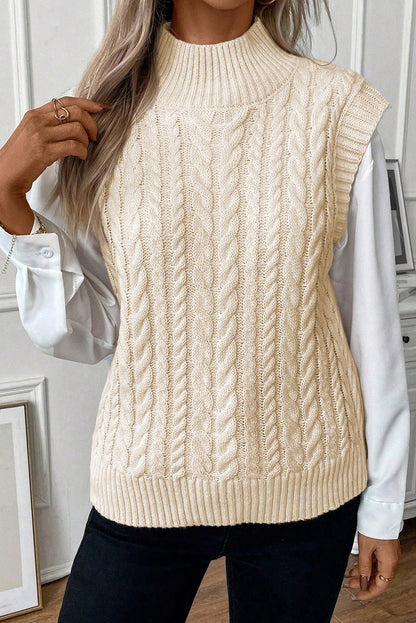 Cable-knit mock neck sweater vest worn over a white shirt.