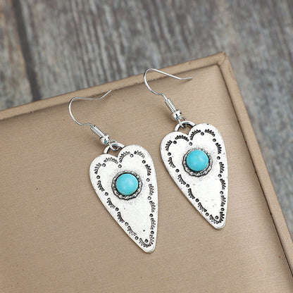 Alloy turquoise heart dangle earrings with silver-plated finish on display.