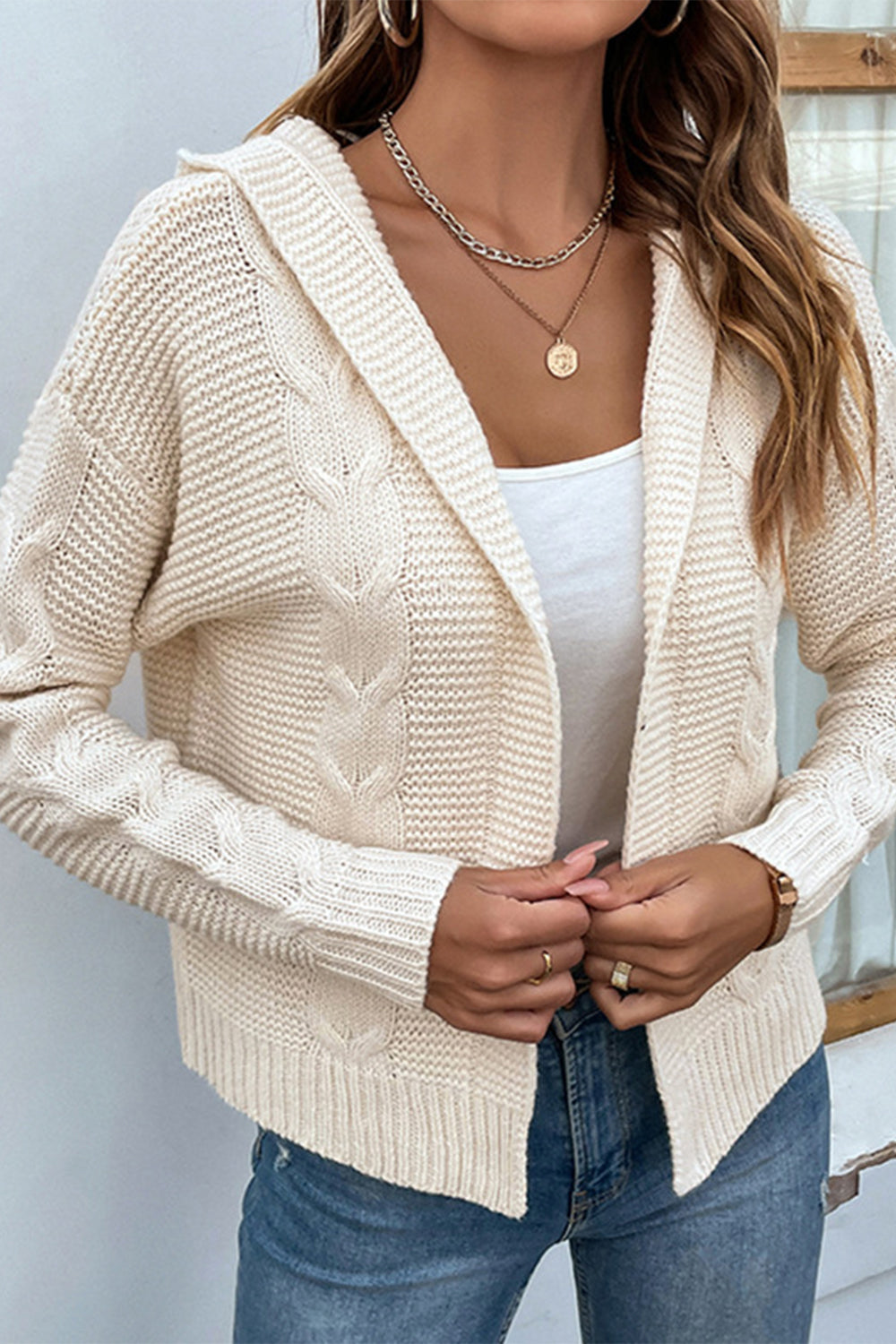 Cable-knit dropped shoulder hooded cardigan in ivory, featuring a cable-knit pattern, open front design, and long sleeves. Perfect for layering and winter style.