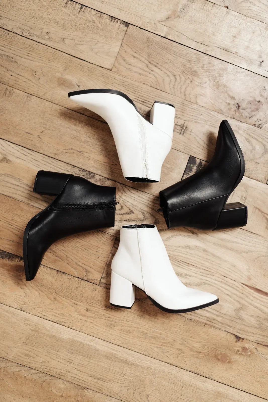 Amari Ankle Boots in white faux leather with pointed toe on wooden floor.