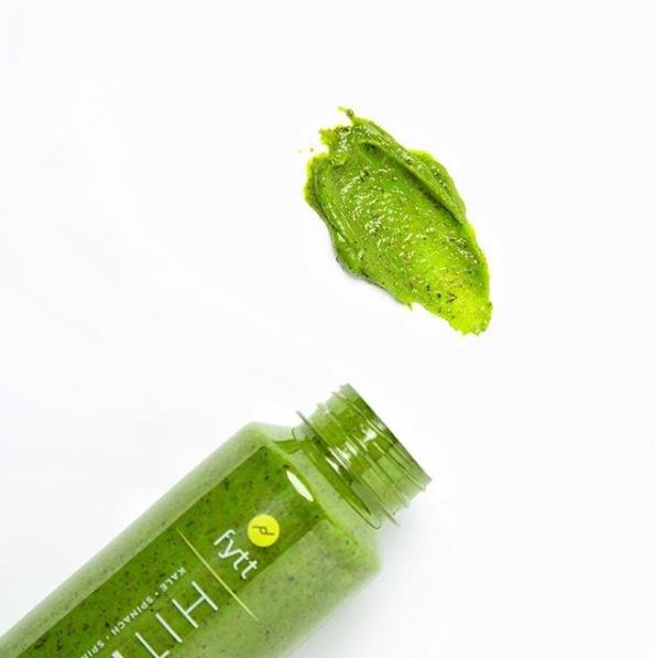 Green detoxifying exfoliating mask sample next to a bottle on a white background.