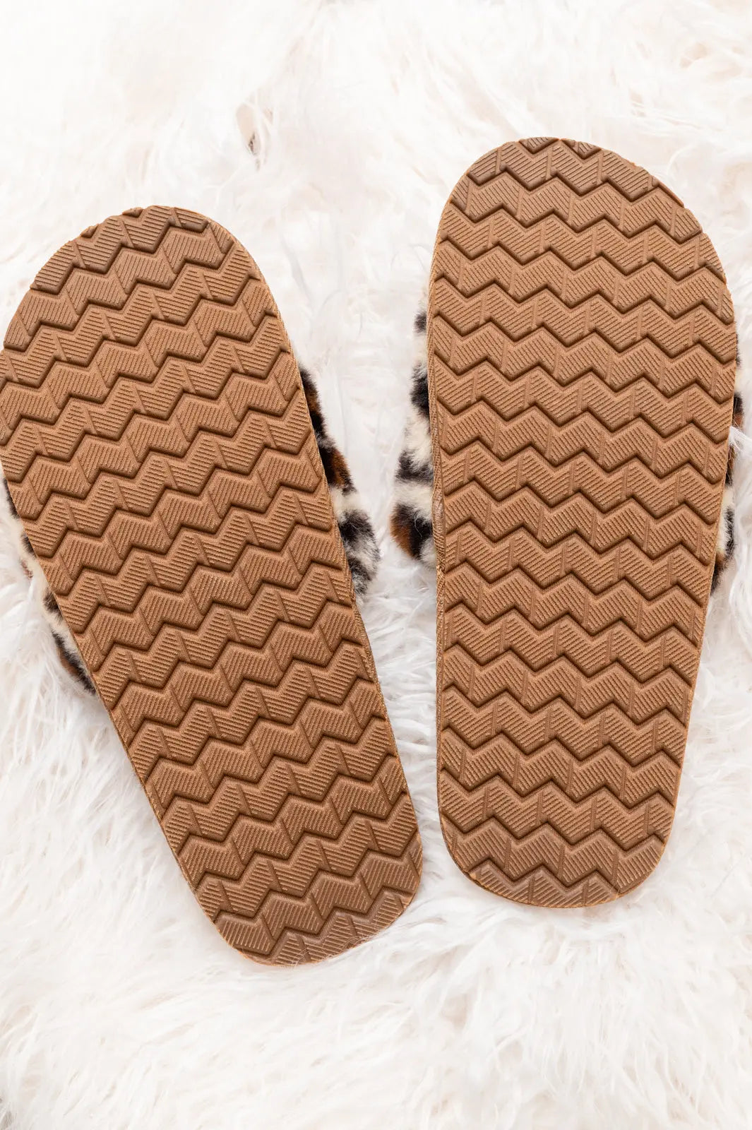 Animal print slippers with faux fur, open toe design, and horse bit detail on a fluffy surface.