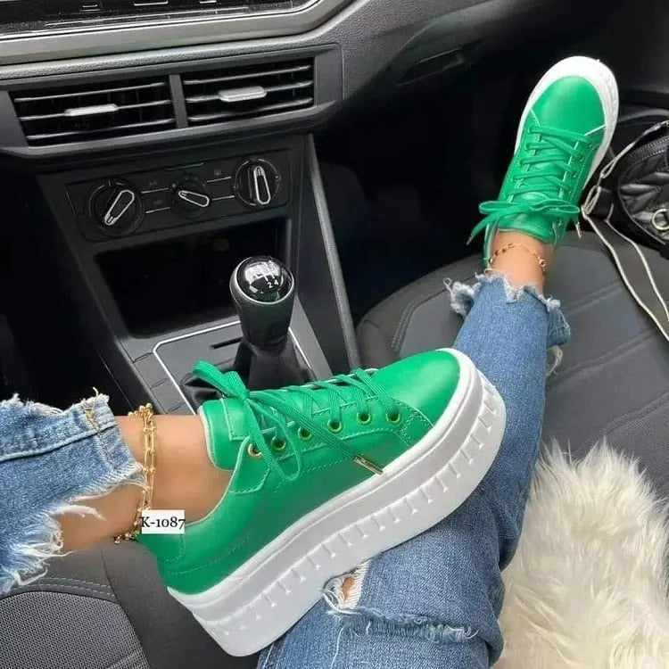 Green casual platform women's sneakers with thick white soles worn in a car setting.