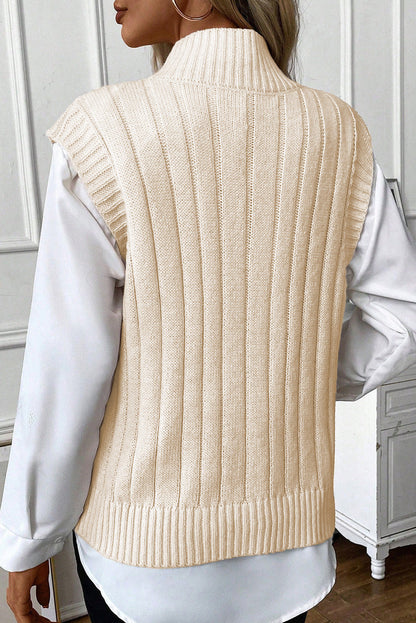 Cable-knit mock neck sweater vest in cream, worn over white shirt.