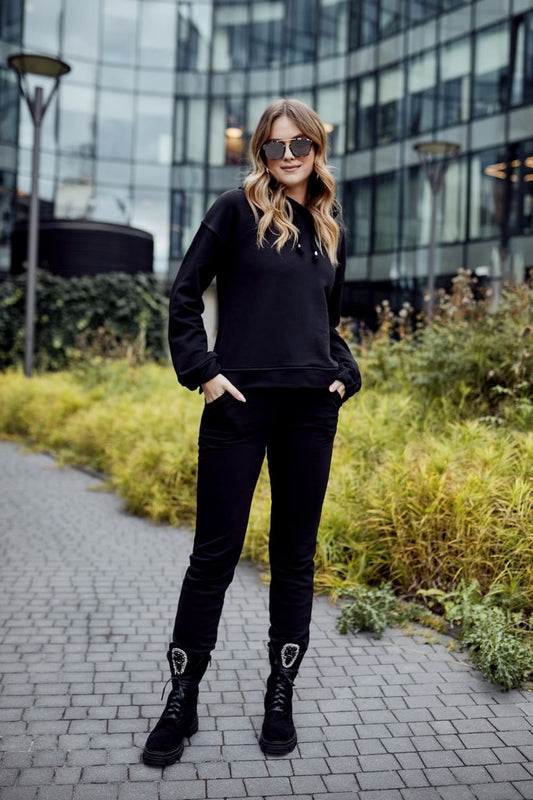 Black women's cotton tracksuit set styled outdoors, featuring a loose pullover and joggers, perfect for casual wear.