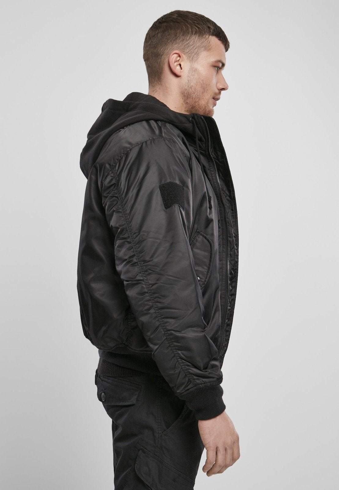 Hooded MA1 Bomber Jacket in black with sweat hood and drawstring, side and arm pockets, worn by model.