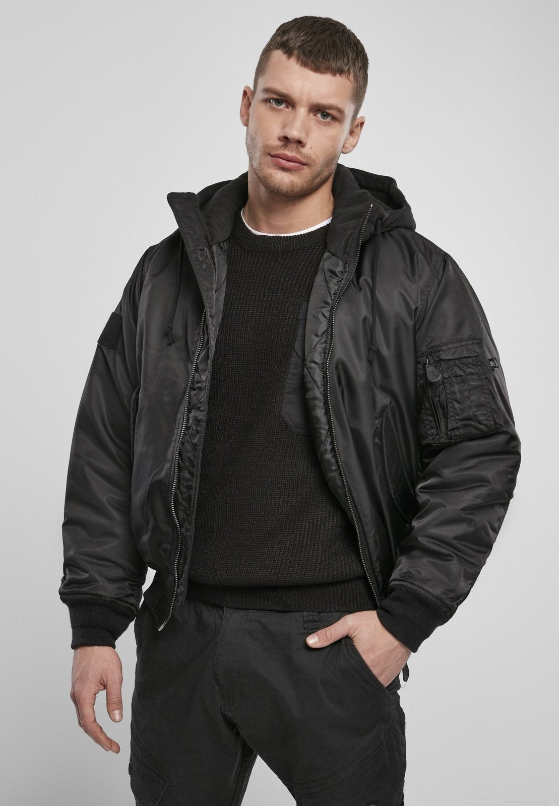 Man wearing black Hooded MA1 Bomber Jacket with sweat hood and knitted cuffs.